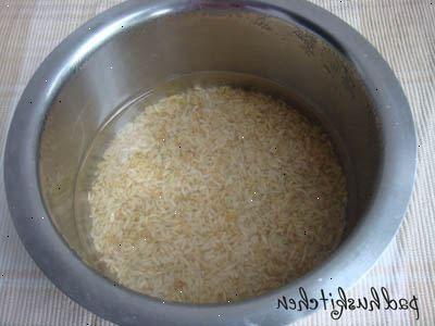 Hoe je rijst koken in een rijstkoker. Meet de rijst met een beker en zet het in je kookpot.