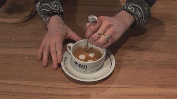 Hoe maak je een macchiato koffie. Met de punt van de spuitmond op het oppervlak van de melk.